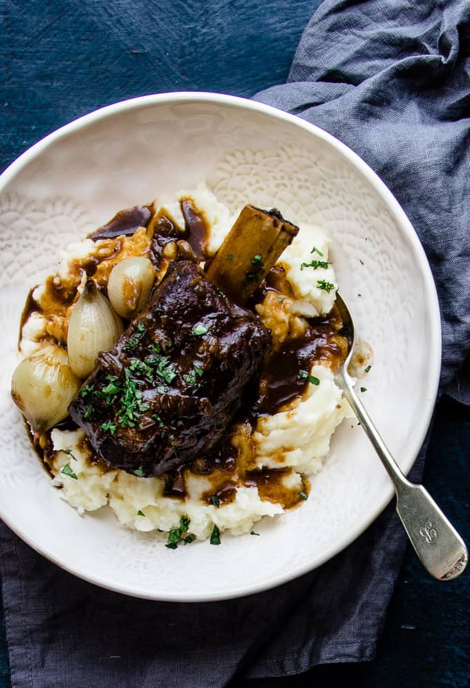 These slow cooker beer braised beef short ribs are a cozy fall off the bone winter classic. Tender, melting beef, dark micro brew ale mixed with spices and savoury beef stock are the perfect winter warmer. They're a no maintenance dinner that is perfect for freezing ahead of a busy week. #beef #shortribs #winter #dinner #makeaheadfreezer #mealprep