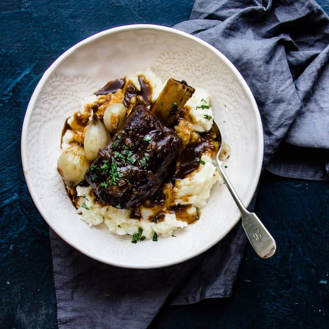 These slow cooker beer braised beef short ribs are a cozy fall off the bone winter classic. Tender, melting beef, dark micro brew ale mixed with spices and savoury beef stock are the perfect winter warmer. They're a no maintenance dinner that is perfect for freezing ahead of a busy week. #beef #shortribs #winter #dinner #makeaheadfreezer #mealprep