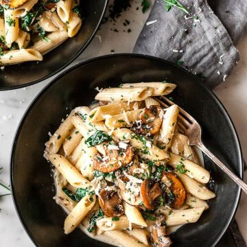 Bowl of creamy mushroom pasta with fork and napkin.