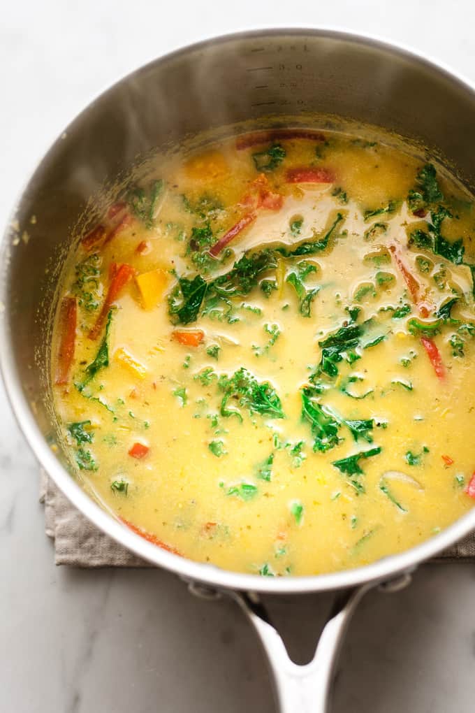Thai yellow curry and sweet potato soup in a pan with kale and red pepper.