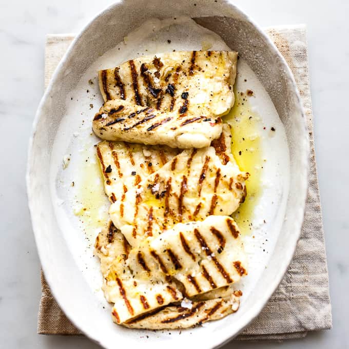 Grilled halloumi in a bowl with olive oil and salt.