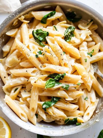 Lemon and artichoke pasta with spinach in a pan.