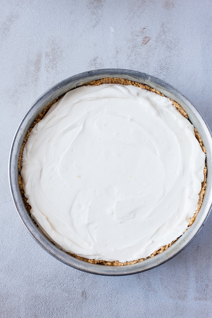 Lemon cheesecake in a cake pan ready for chilling.