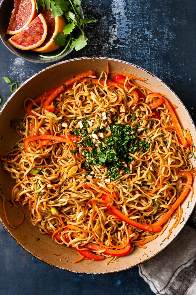 Thai peanut noodles in a non-stick frying pan with cilantro and red pepper.