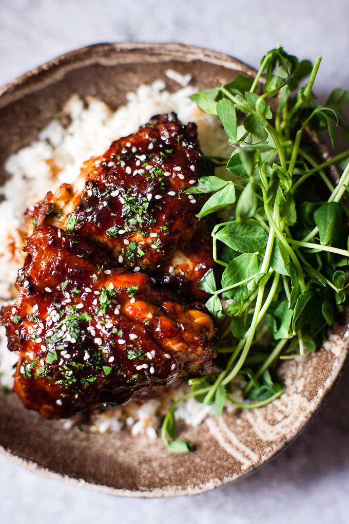Baked Honey chicken in a bowl with sesame seeds, rice and greens.