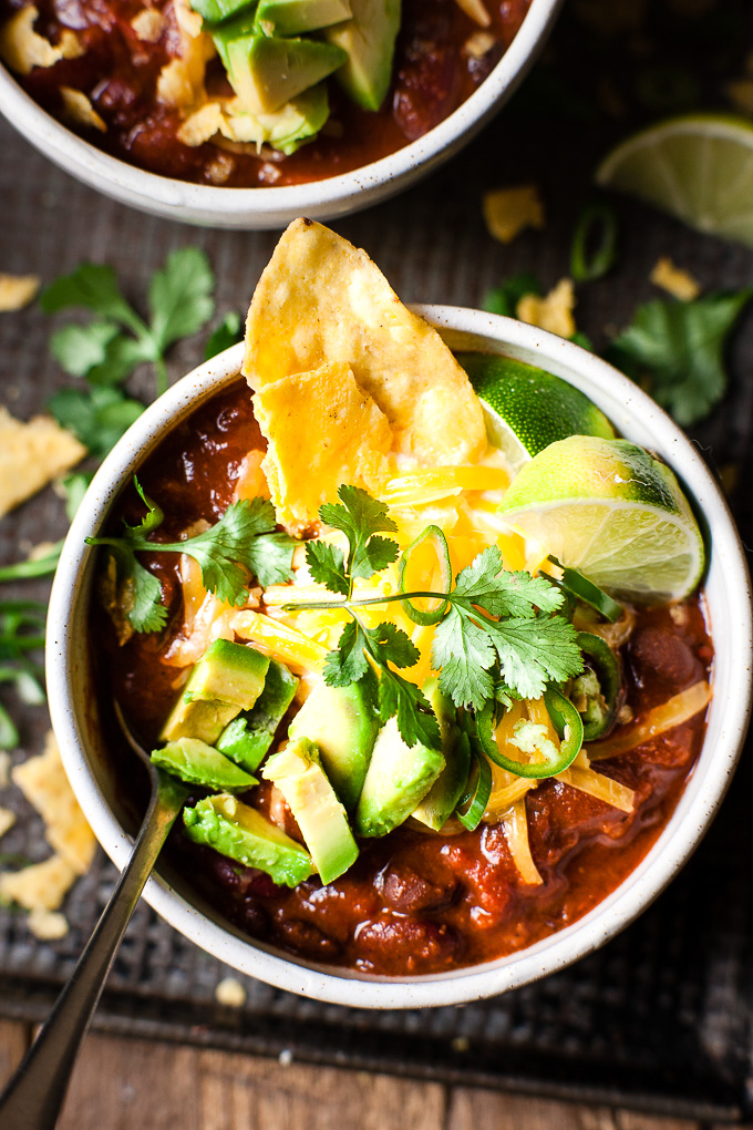 Vegetarian Black bean chili in a bowl with tortilla chips and avocado. 