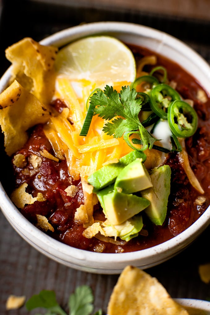 Close up of black bean chili with grated cheese and avocado.