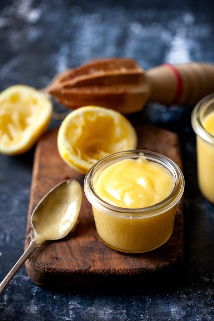 Jar of lemon curd on a wooden board with spoons