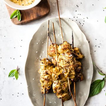Oven-grilled chicken skewers on a grey plate.