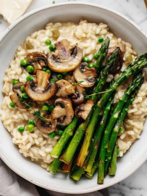 Creamy mushroom and asparagus risotto in a white bowl.