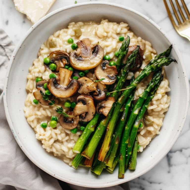 Creamy mushroom and asparagus risotto in a white bowl.