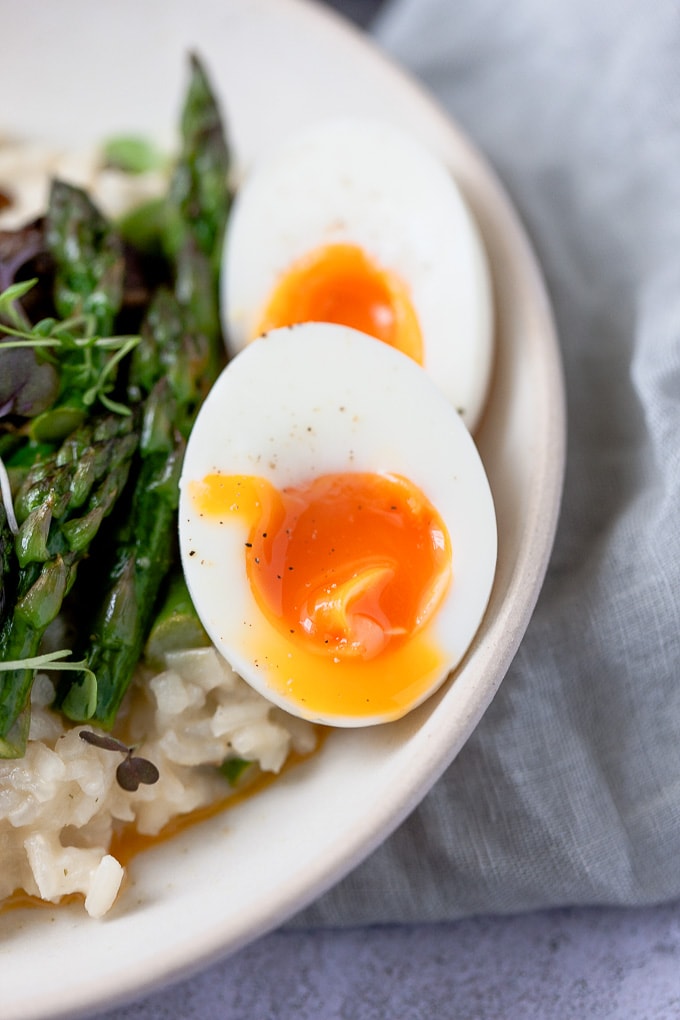 Soft-boiled egg sitting on top of asparagus risotto.