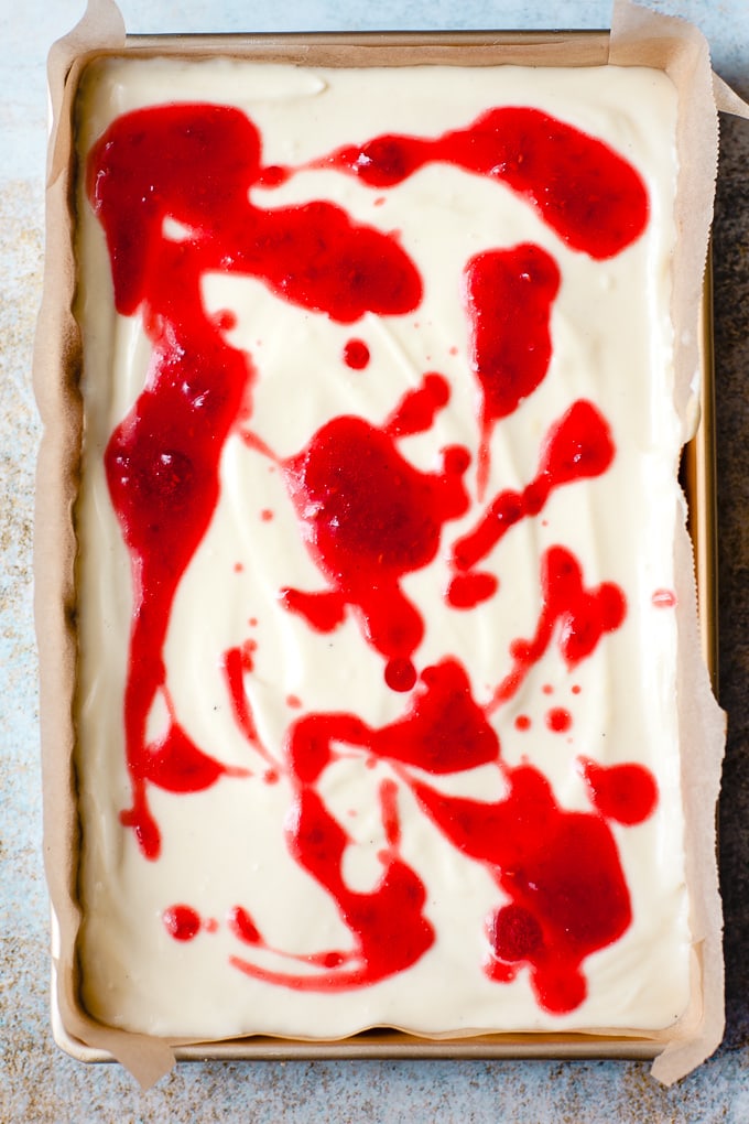 Raspberry sauce being swirled in to cheesecake.