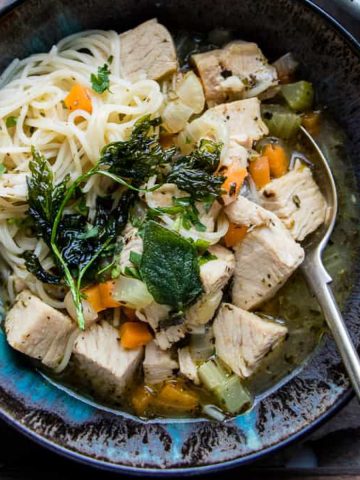 Italian chicken noodle soup in a blue bowl.