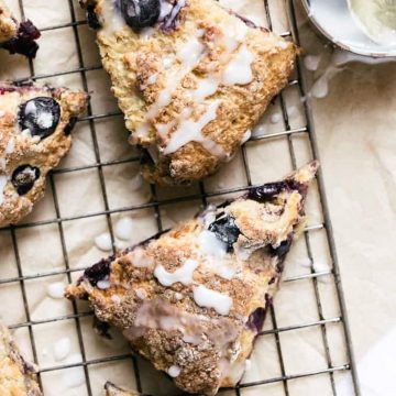 Blueberry scones with lemon glaze on a cooling rack.