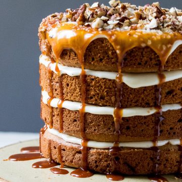 Caramel pecan cake with chopped pecans on a cake stand.