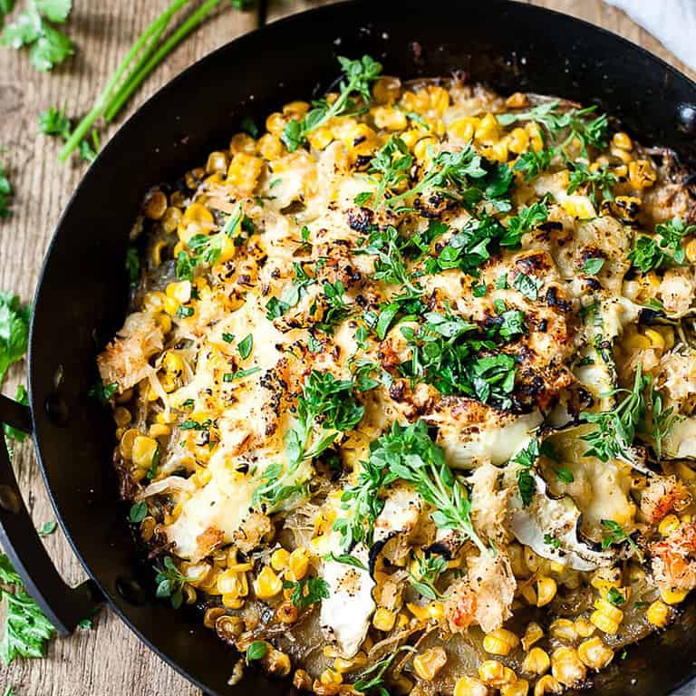 Corn and potato bake in a skillet on a table.