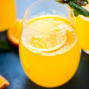 Orange Ginger Immune boosting elixir in a bottle with a glass on the side.