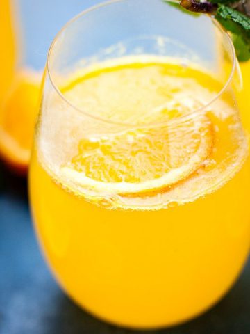 Orange Ginger Immune boosting elixir in a bottle with a glass on the side.