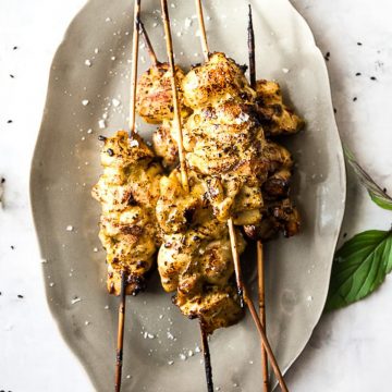 Oven-grilled chicken skewers on a grey plate.
