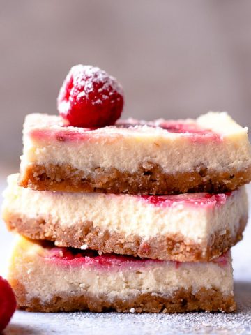 Stack of three cheesecake bars with raspberries.