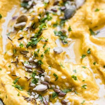 Roasted carrot hummus with olive oil and seeds.