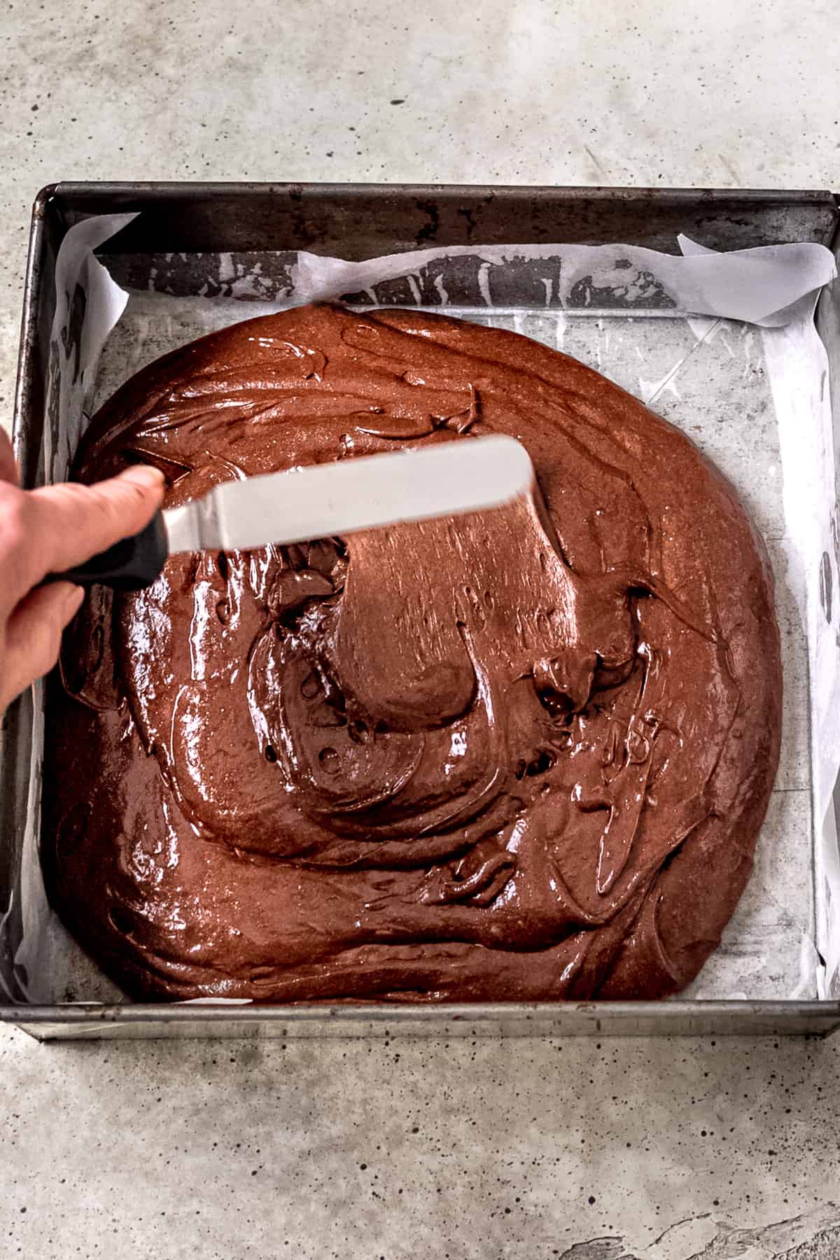 Brownie batter in a lined baking tin.