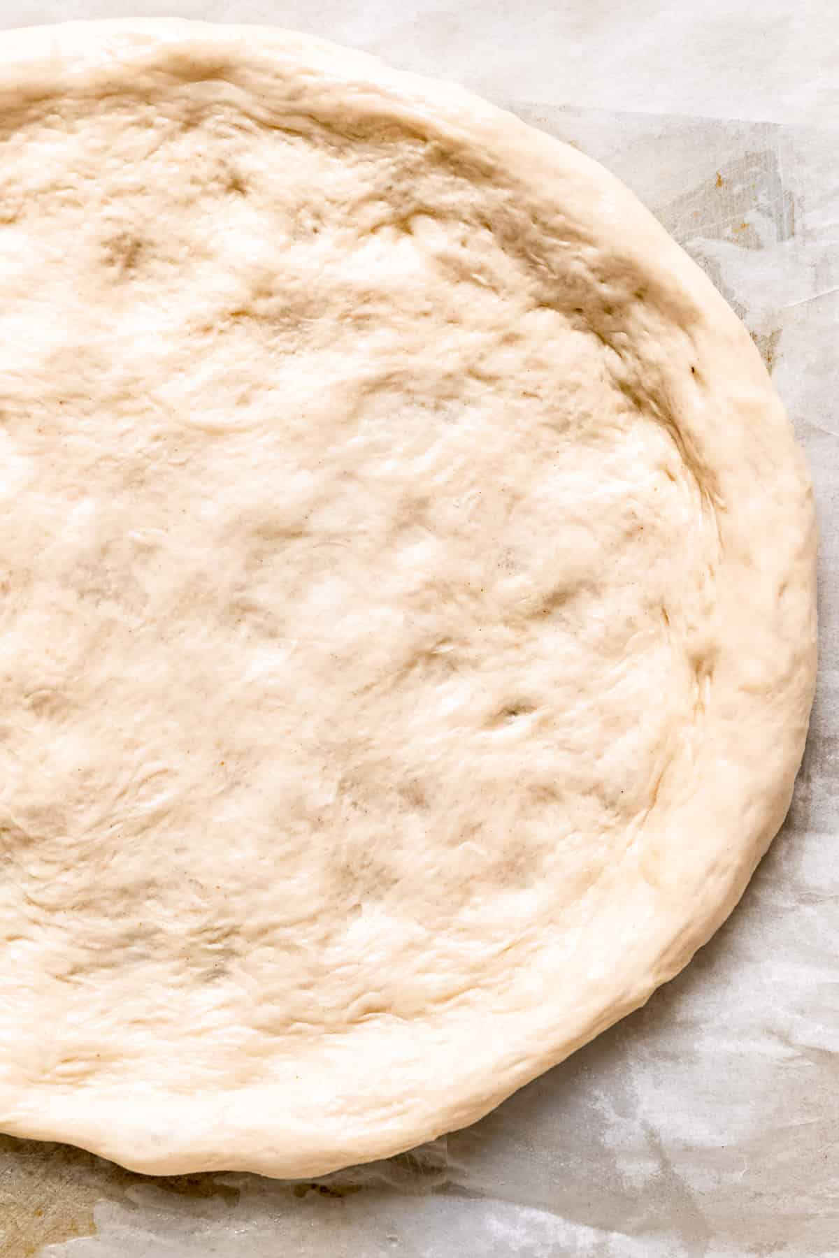 Pizza dough stretched on a baking tray.