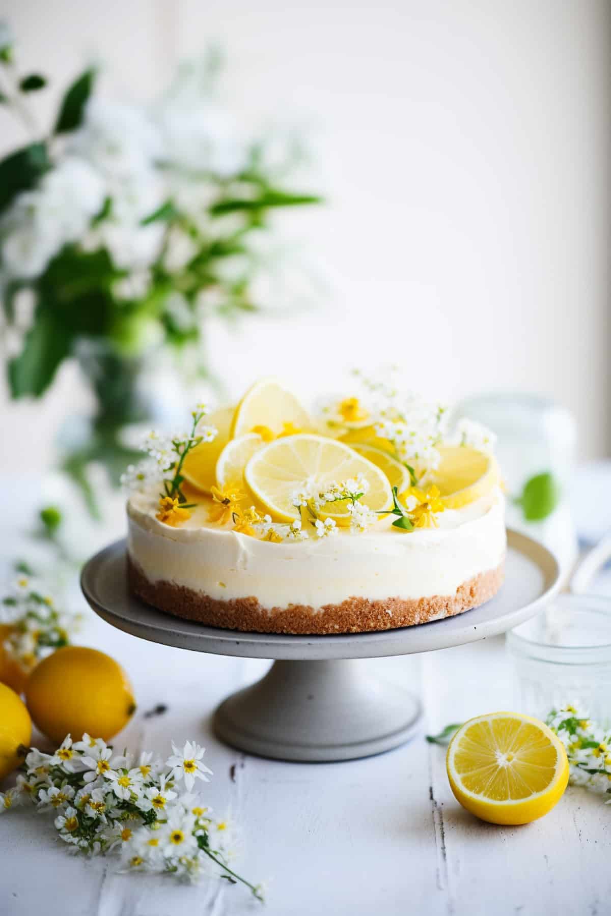 No bake lemon cheesecake on a cake plate with lemon slices.