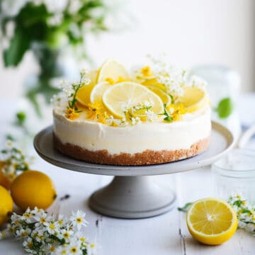 No bake lemon cheesecake on a cake plate with lemon slices.
