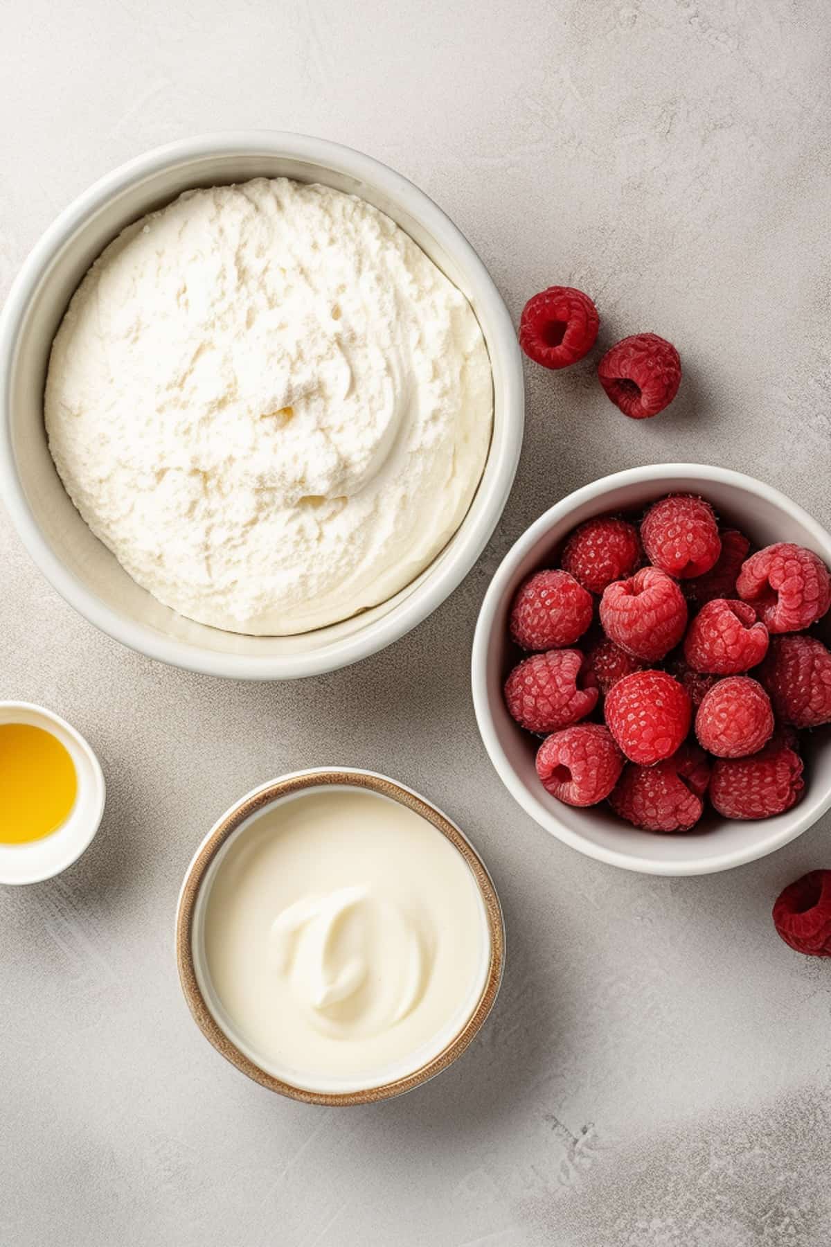 Ingredients for raspberry cheesecake bars on a grey table.