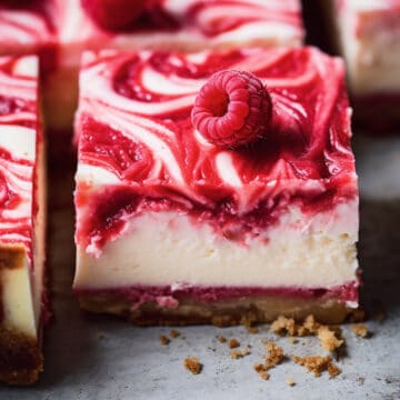 Raspberry cheesecake bars on a baking tray.