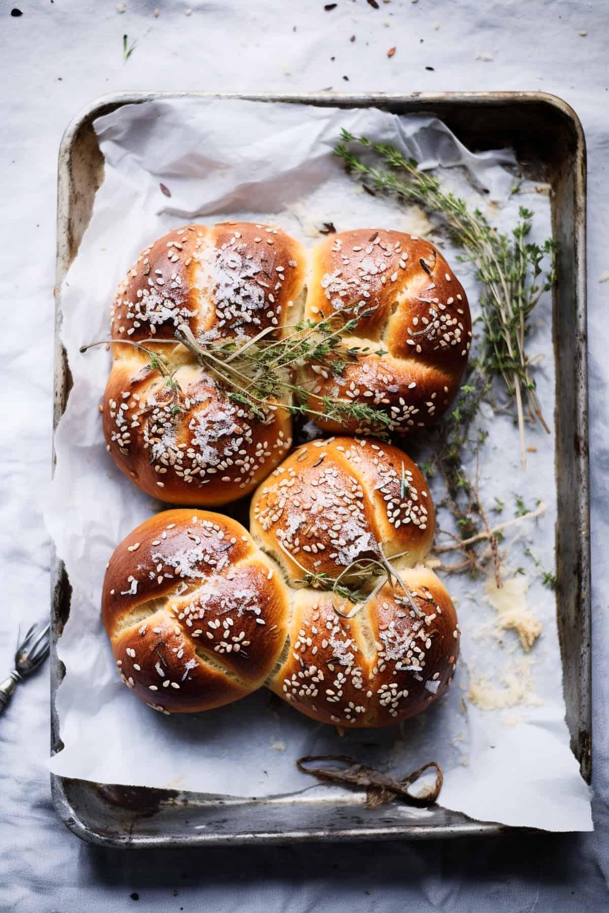 Bread rolls with seeds and herbs in a tray.