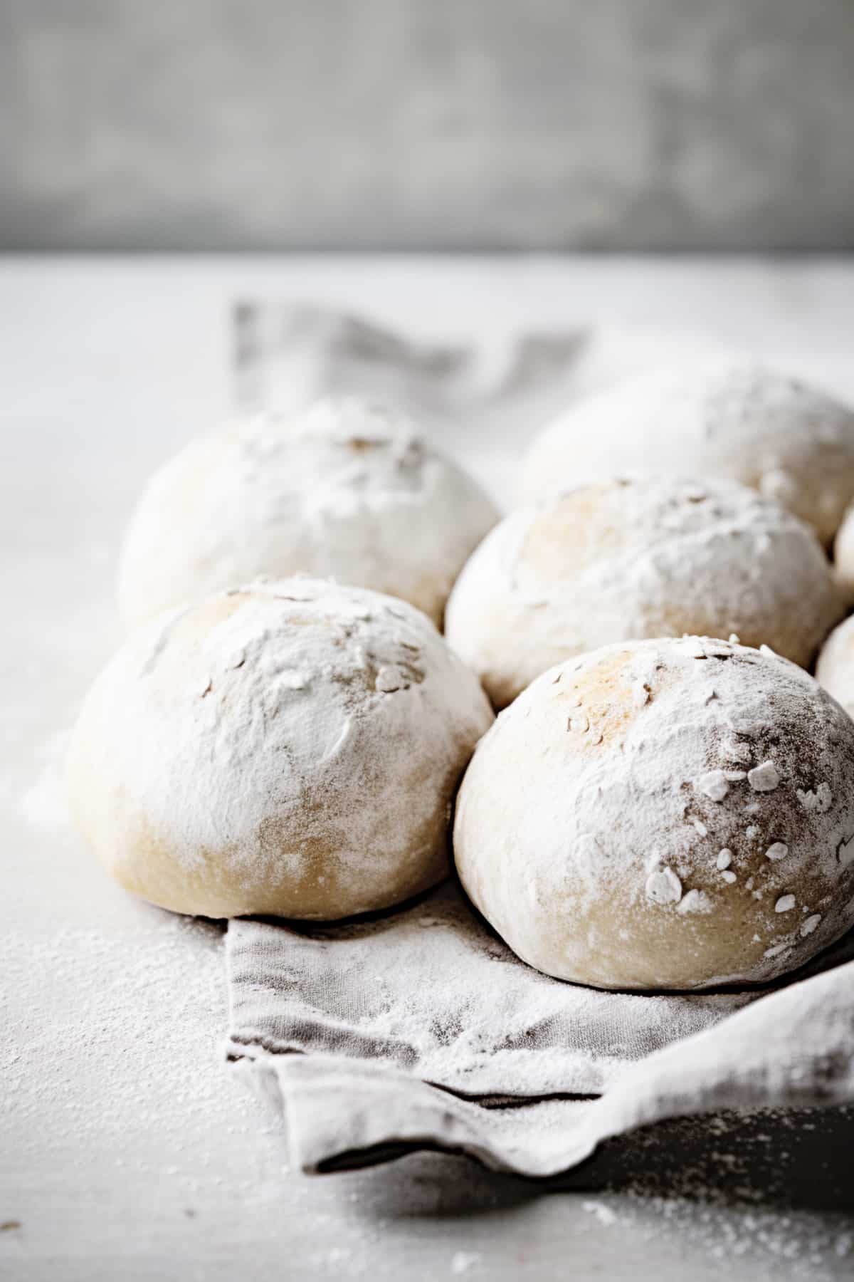 Unbaked bread rolls on a floured surface.
