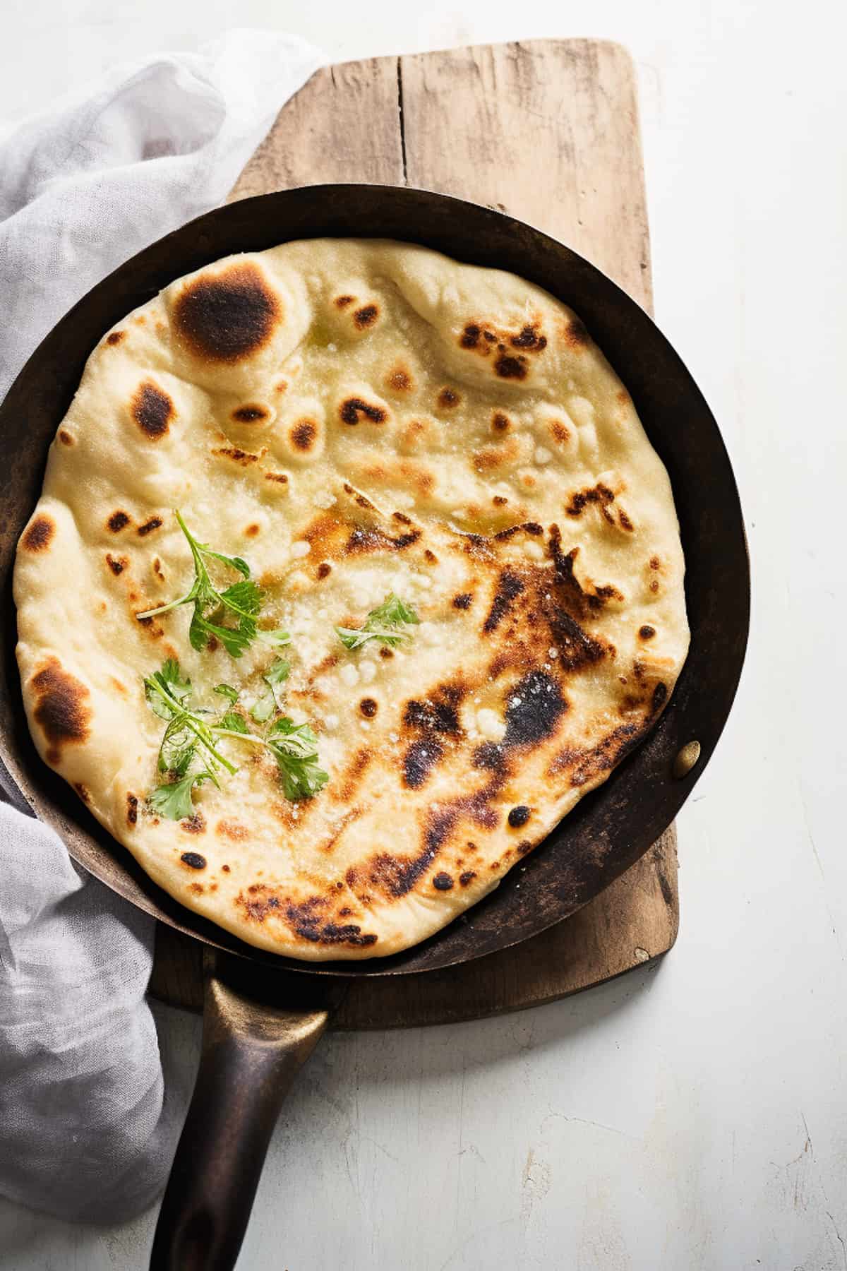 Naan bread being cooked in a skillet.