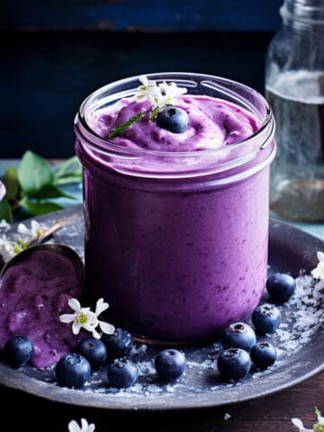 Blueberry curd in a jar with fresh blueberries.