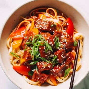 Korean noodle stir fry with beef on a marble table.