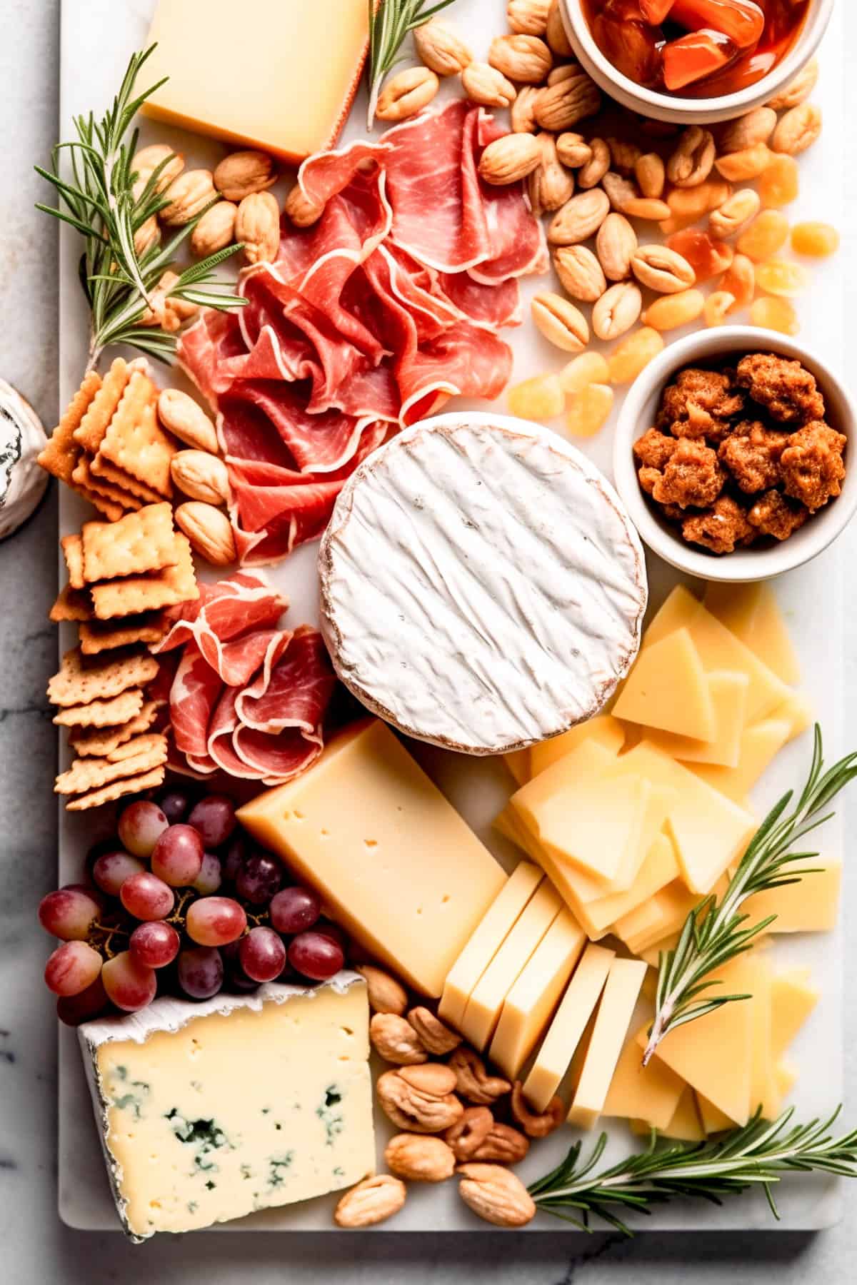 A selection of cheeses on a cheeseboard with charcuterie and condiments.