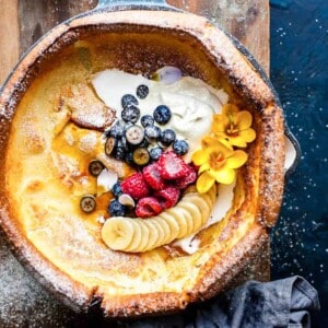Dutch baby pancake with cream and maple syrup in a skillet.