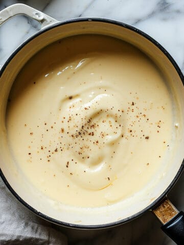 Easy bechamel sauce made without flour in a sauce pan with pepper.