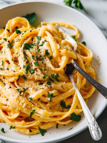 Creamy pumpkin alfredo with parmesan cheese in a white bowl.