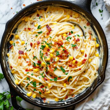 Creamy corn and bacon pasta in a sauce pan with parsley.