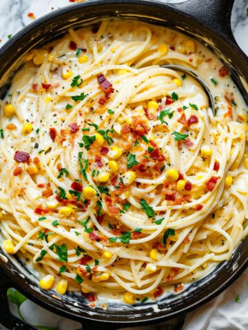 Creamy corn and bacon pasta in a sauce pan with parsley.