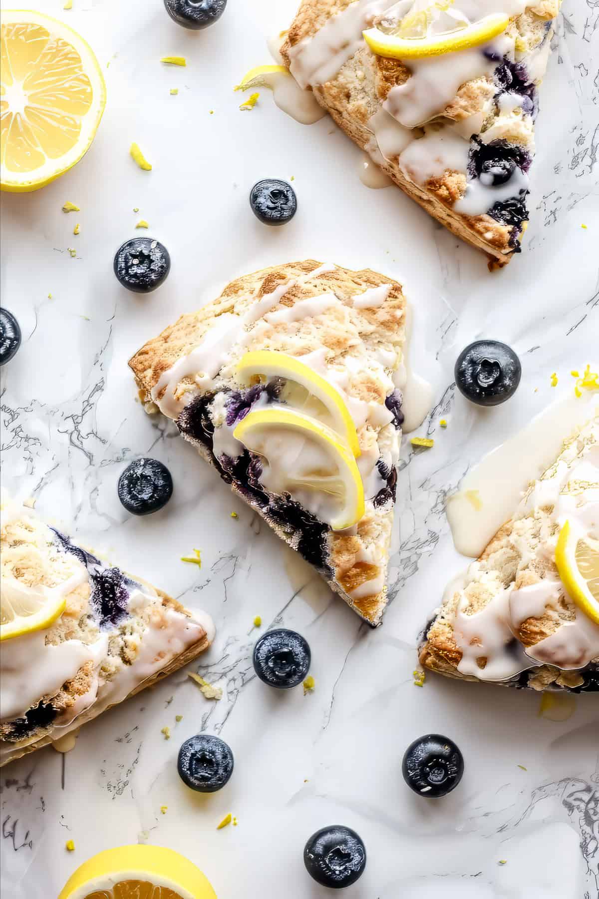 Blueberry lemon Scones with glaze on a white table.