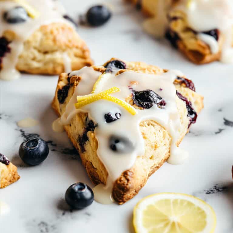 Blueberry lemon Scones with glaze on a white table.