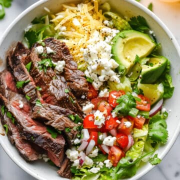 Carne asada bowls with salad and cotija cheese.
