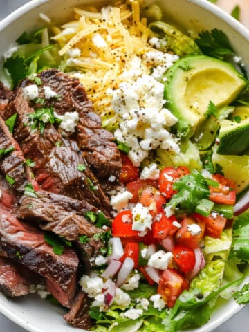 Carne asada bowls with salad and cotija cheese.
