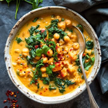 Chick pea coconut curry with spinach and cilantro in a white bowl.