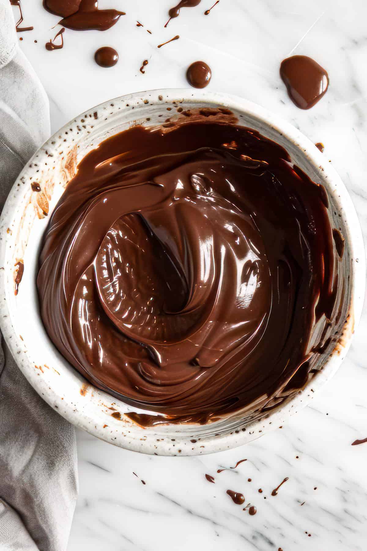 Chocolate ganache for tart in a white bowl.