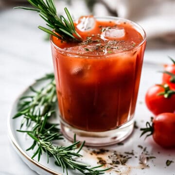 Bloody mary cocktail with rosemary and ice in a glass.